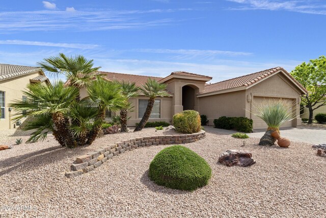 mediterranean / spanish-style home featuring stucco siding, an attached garage, driveway, and a tile roof