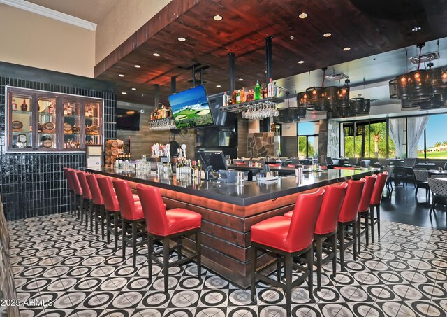 bar featuring recessed lighting, a bar, and ornamental molding