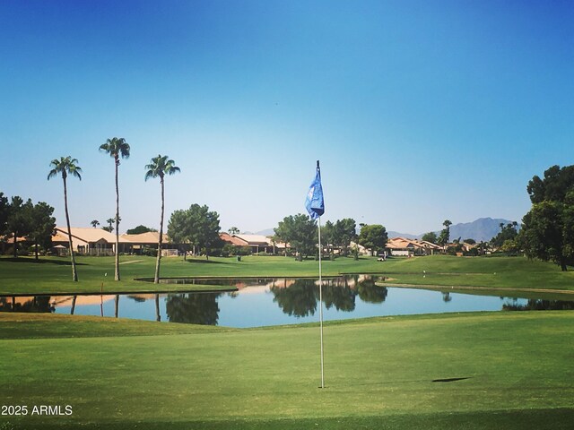 view of home's community with a yard, a residential view, view of golf course, and a water and mountain view