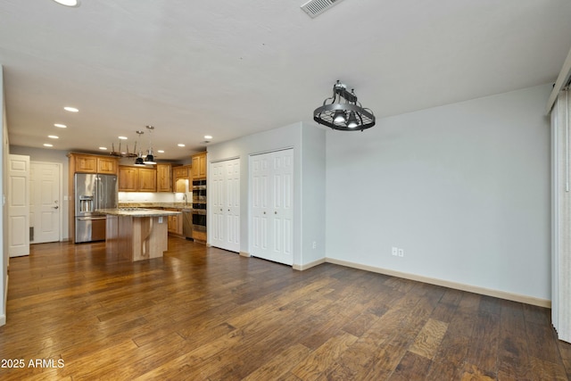 kitchen with a kitchen island, high quality fridge, a breakfast bar, dark hardwood / wood-style flooring, and hanging light fixtures