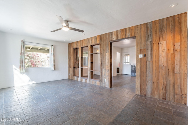 empty room featuring wooden walls and a ceiling fan