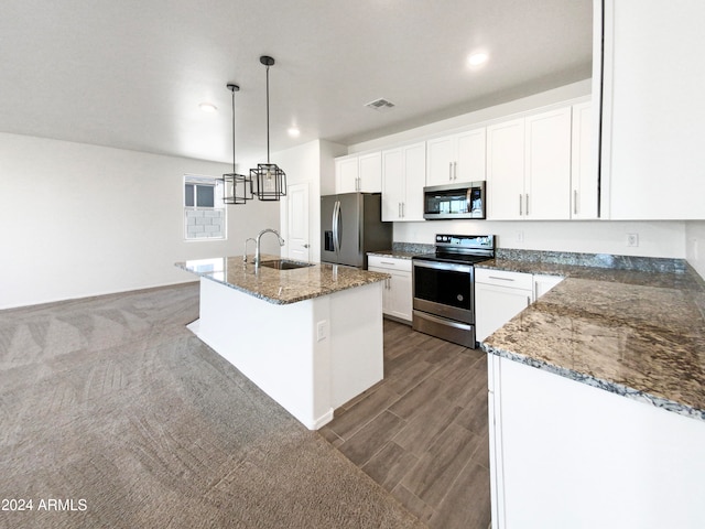 kitchen featuring pendant lighting, a kitchen island with sink, sink, white cabinets, and stainless steel appliances