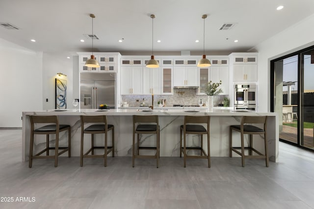 kitchen featuring tasteful backsplash, visible vents, stainless steel appliances, and a large island