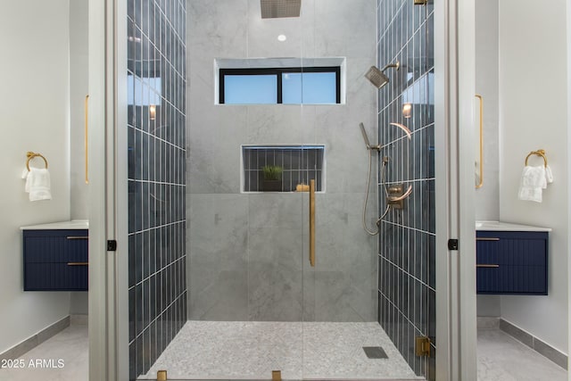 bathroom featuring a tile shower, vanity, and baseboards