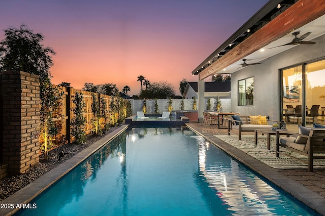 pool at dusk with ceiling fan, a patio, a fenced backyard, and a fenced in pool