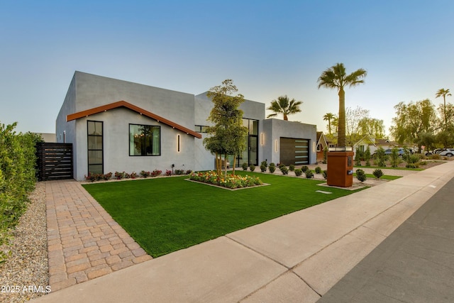 modern home with a front lawn, fence, and stucco siding