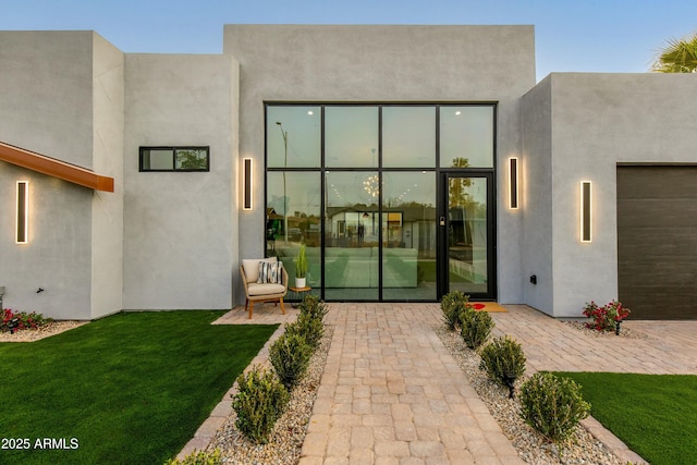 back of property with a patio area, a lawn, and stucco siding