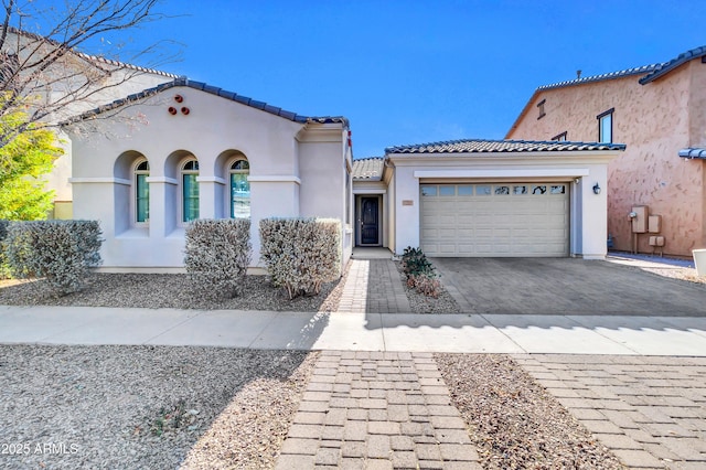 mediterranean / spanish house featuring a tiled roof, a garage, driveway, and stucco siding