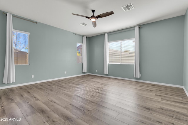 unfurnished room with plenty of natural light, wood finished floors, and visible vents