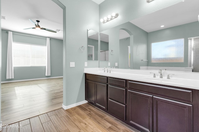 full bath featuring ceiling fan, baseboards, wood tiled floor, double vanity, and a sink