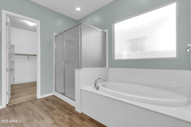 bathroom featuring a wealth of natural light, a walk in closet, a garden tub, and a shower stall