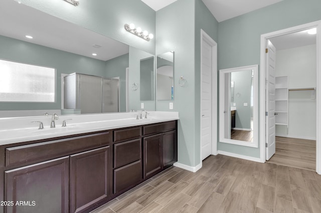 full bath featuring a sink, baseboards, a stall shower, and wood finished floors