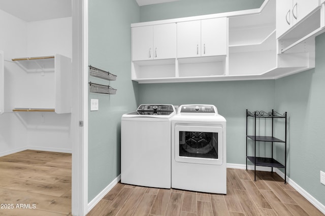 laundry room with washer and dryer, baseboards, cabinet space, and light wood finished floors