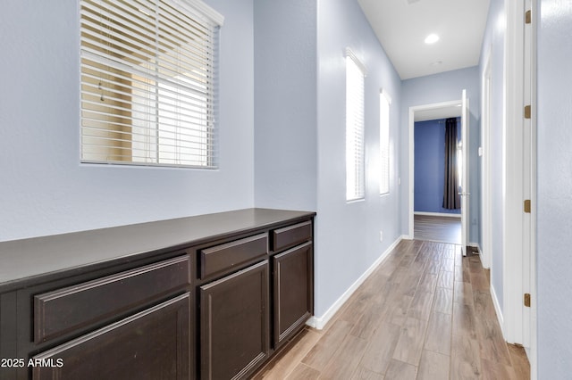 hall with baseboards and light wood-style floors