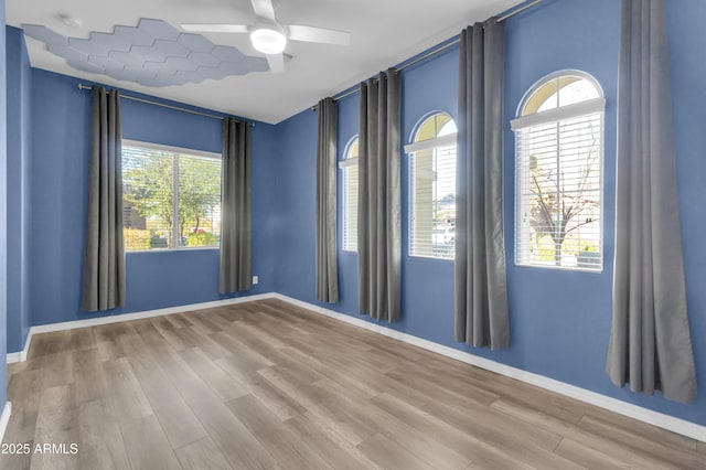 unfurnished room with a ceiling fan, baseboards, and wood finished floors