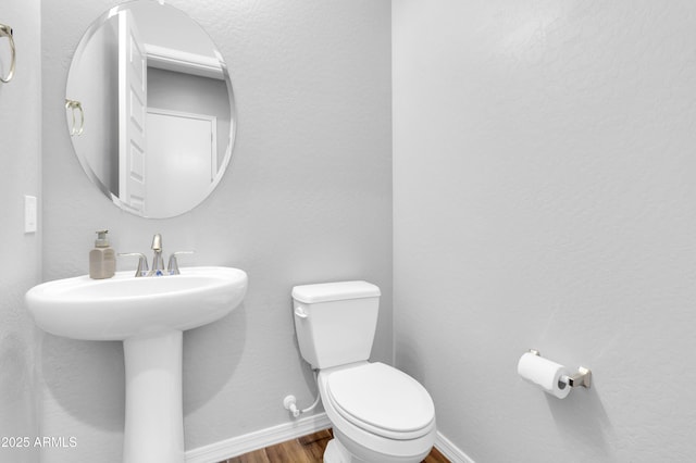 bathroom featuring baseboards, toilet, and wood finished floors