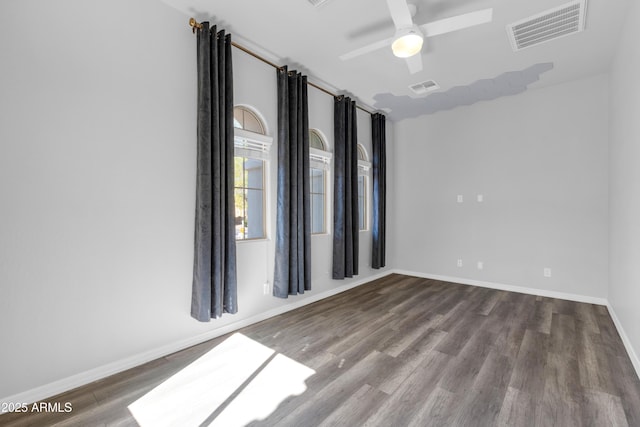 spare room featuring visible vents, ceiling fan, baseboards, and wood finished floors