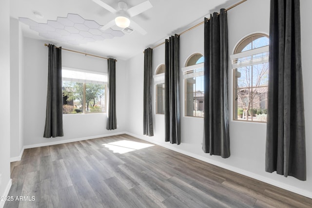 spare room with a ceiling fan, wood finished floors, visible vents, and baseboards