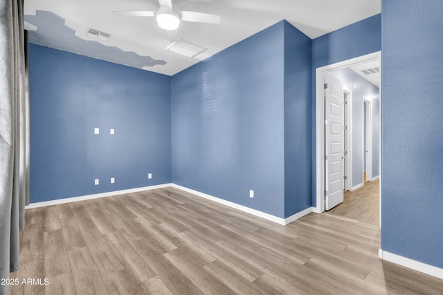 spare room featuring ceiling fan, visible vents, baseboards, and wood finished floors