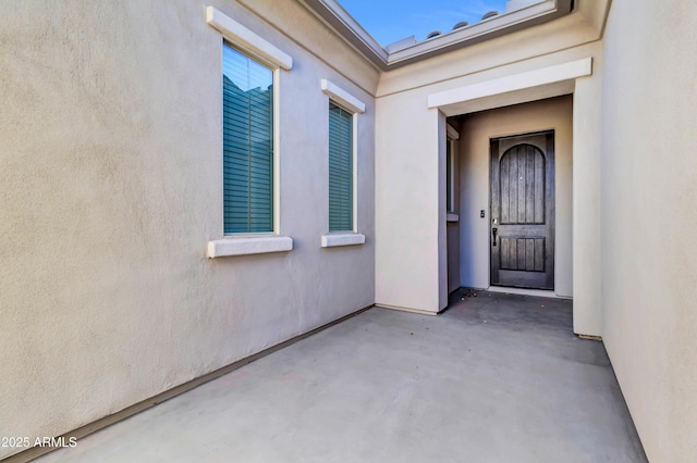 doorway to property featuring a patio area and stucco siding