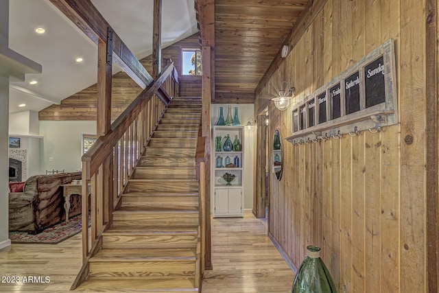 stairs featuring wood ceiling, lofted ceiling, wooden walls, and wood-type flooring