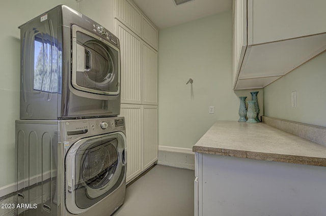 laundry area with stacked washer and dryer and cabinets