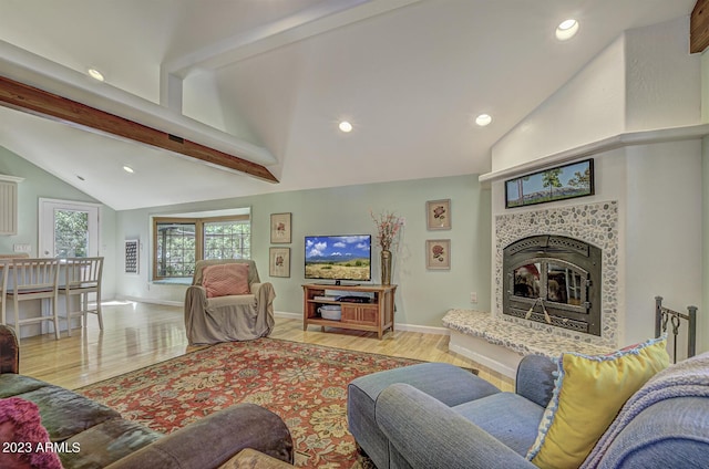 living room with a tiled fireplace, vaulted ceiling with beams, and light hardwood / wood-style flooring