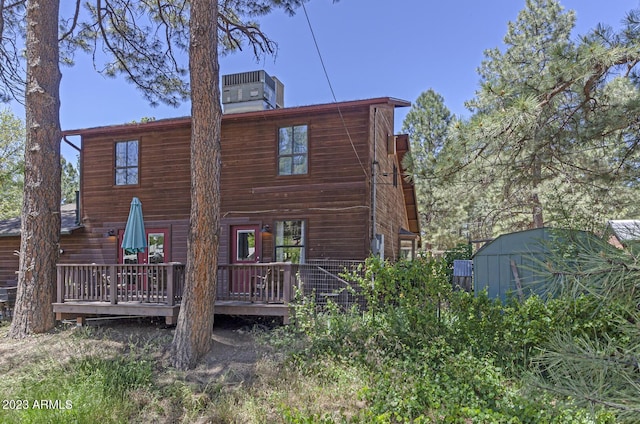 rear view of property featuring a shed, central air condition unit, and a deck