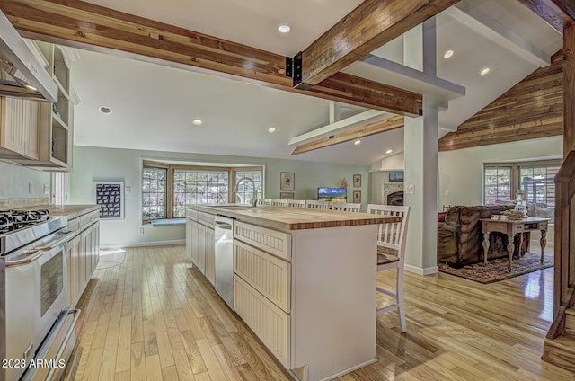 kitchen featuring butcher block countertops, light wood-type flooring, appliances with stainless steel finishes, a kitchen breakfast bar, and a large island