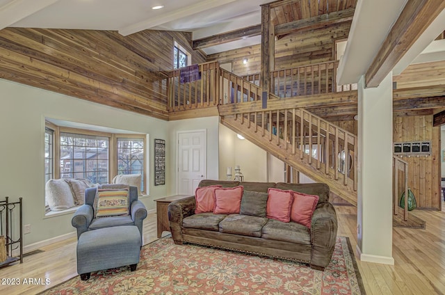 living room with a towering ceiling, beam ceiling, and light hardwood / wood-style flooring