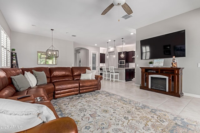 1036 W Siebold Tree Ave, Queen Creek, AZ 85140 - living area featuring a ceiling fan, arched walkways, light tile patterned flooring, a chandelier, and a fireplace