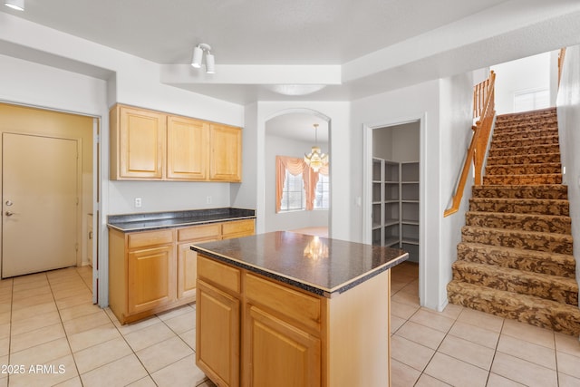 kitchen featuring light tile patterned floors, light brown cabinetry, dark countertops, and a kitchen island