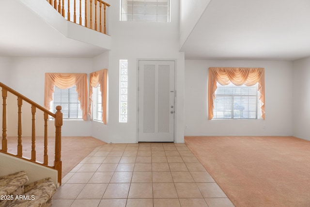 foyer entrance with light carpet, plenty of natural light, and stairway