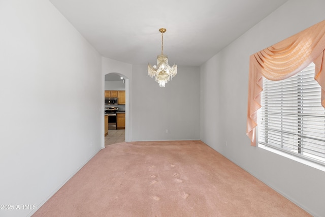 unfurnished room featuring arched walkways, light carpet, and a notable chandelier