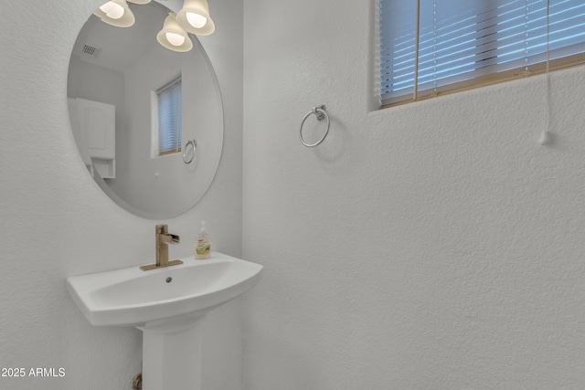 bathroom with a sink, visible vents, and a textured wall