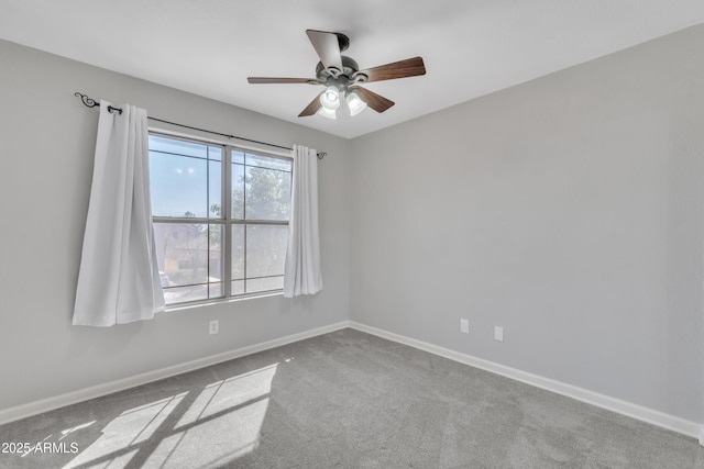 carpeted spare room featuring a ceiling fan and baseboards