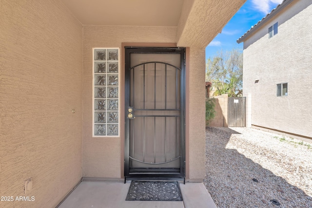 property entrance featuring a gate and stucco siding