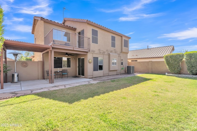 back of property with a fenced backyard, a lawn, a balcony, and stucco siding