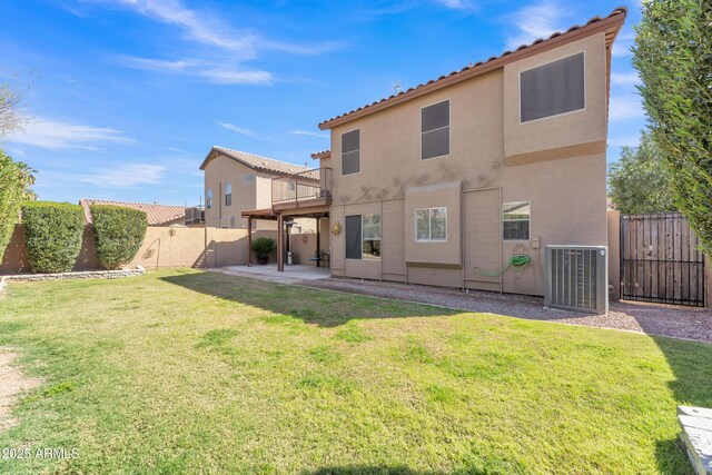 rear view of house with central air condition unit, stucco siding, a lawn, a patio, and a fenced backyard