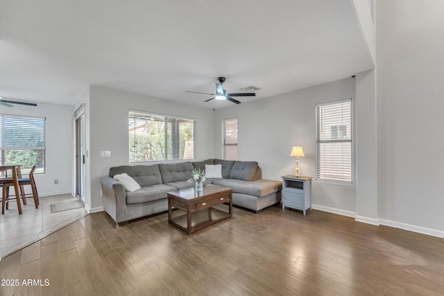 living room with wood finished floors, a ceiling fan, and a healthy amount of sunlight