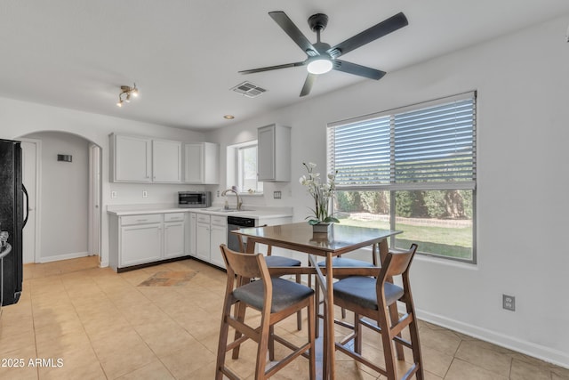 dining space with light tile patterned floors, a ceiling fan, visible vents, baseboards, and arched walkways