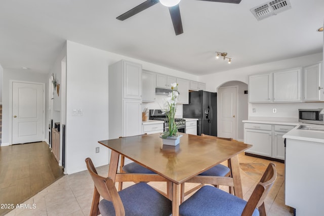 dining area featuring visible vents, arched walkways, light tile patterned flooring, and a ceiling fan