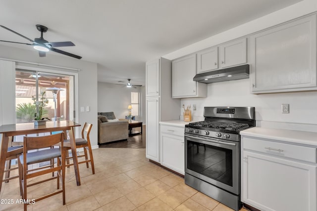 kitchen with under cabinet range hood, light tile patterned floors, light countertops, and gas stove