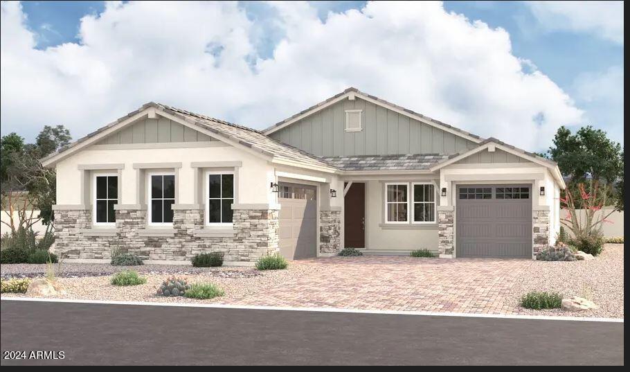 craftsman-style house featuring a garage, stone siding, board and batten siding, and decorative driveway