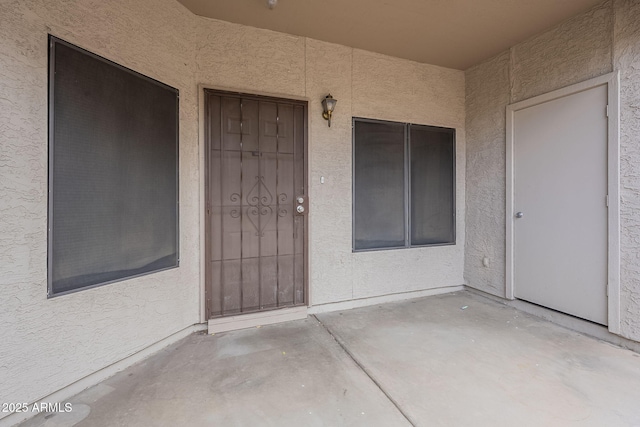 entrance to property featuring a patio area and stucco siding