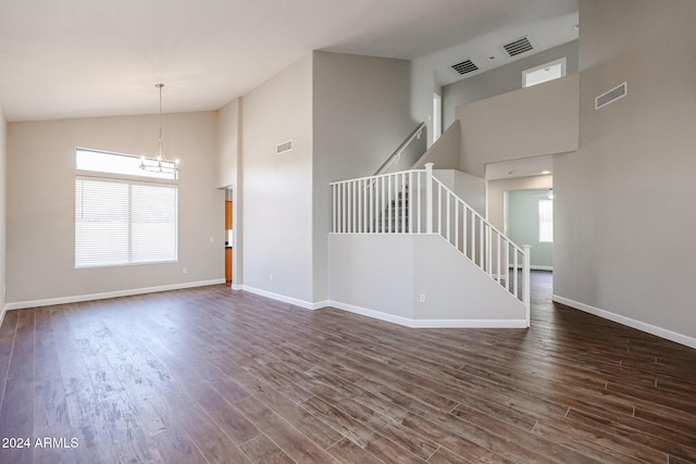 unfurnished living room featuring dark hardwood / wood-style flooring, a towering ceiling, and a healthy amount of sunlight