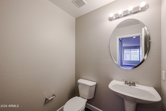 bathroom with vaulted ceiling, toilet, and sink