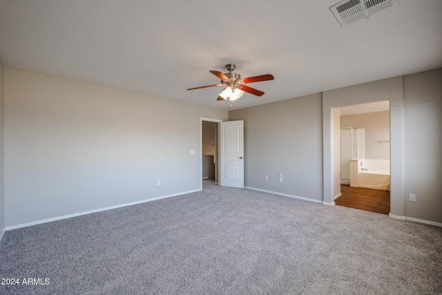 unfurnished bedroom featuring ceiling fan, ensuite bathroom, and dark colored carpet