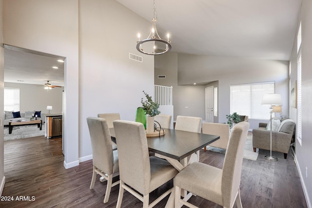 dining area with high vaulted ceiling, dark wood-type flooring, and ceiling fan with notable chandelier