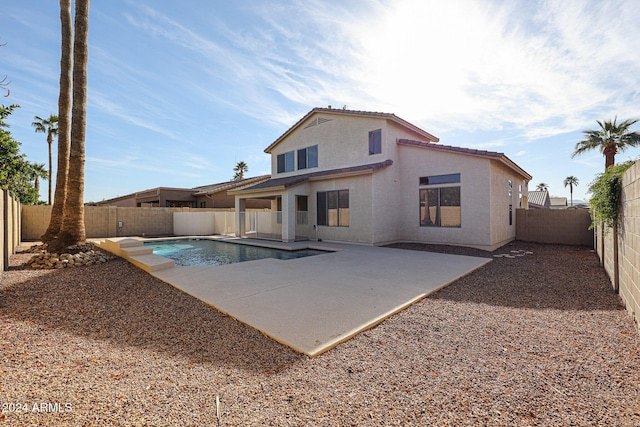 rear view of house featuring a patio and a fenced in pool